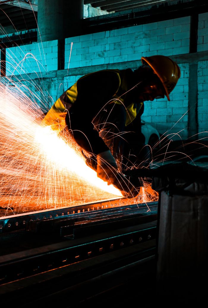 Soldador trabajando con chispas sobre estructura metálica
