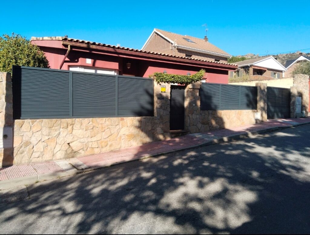 Vallado metálico sobre muro de piedra en vivienda unifamiliar